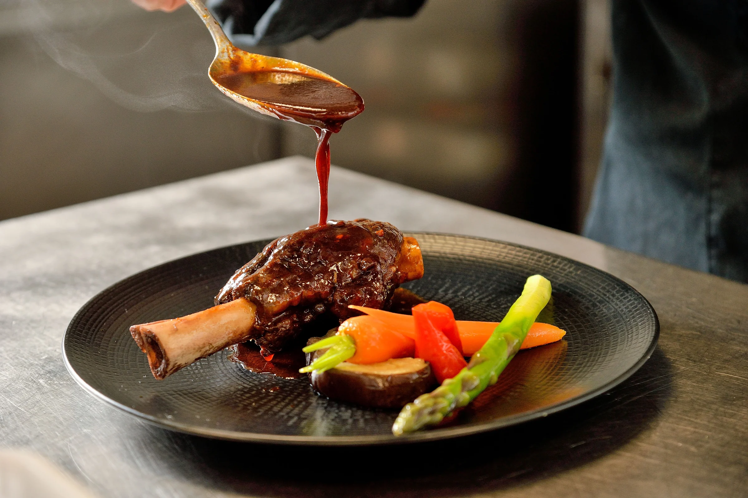 Une sauce versée sur une assiette de viande et de légumes au Bistrot des Uttins