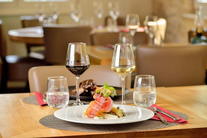 Une assiette et ses verres de vin sur une table du Bistrot